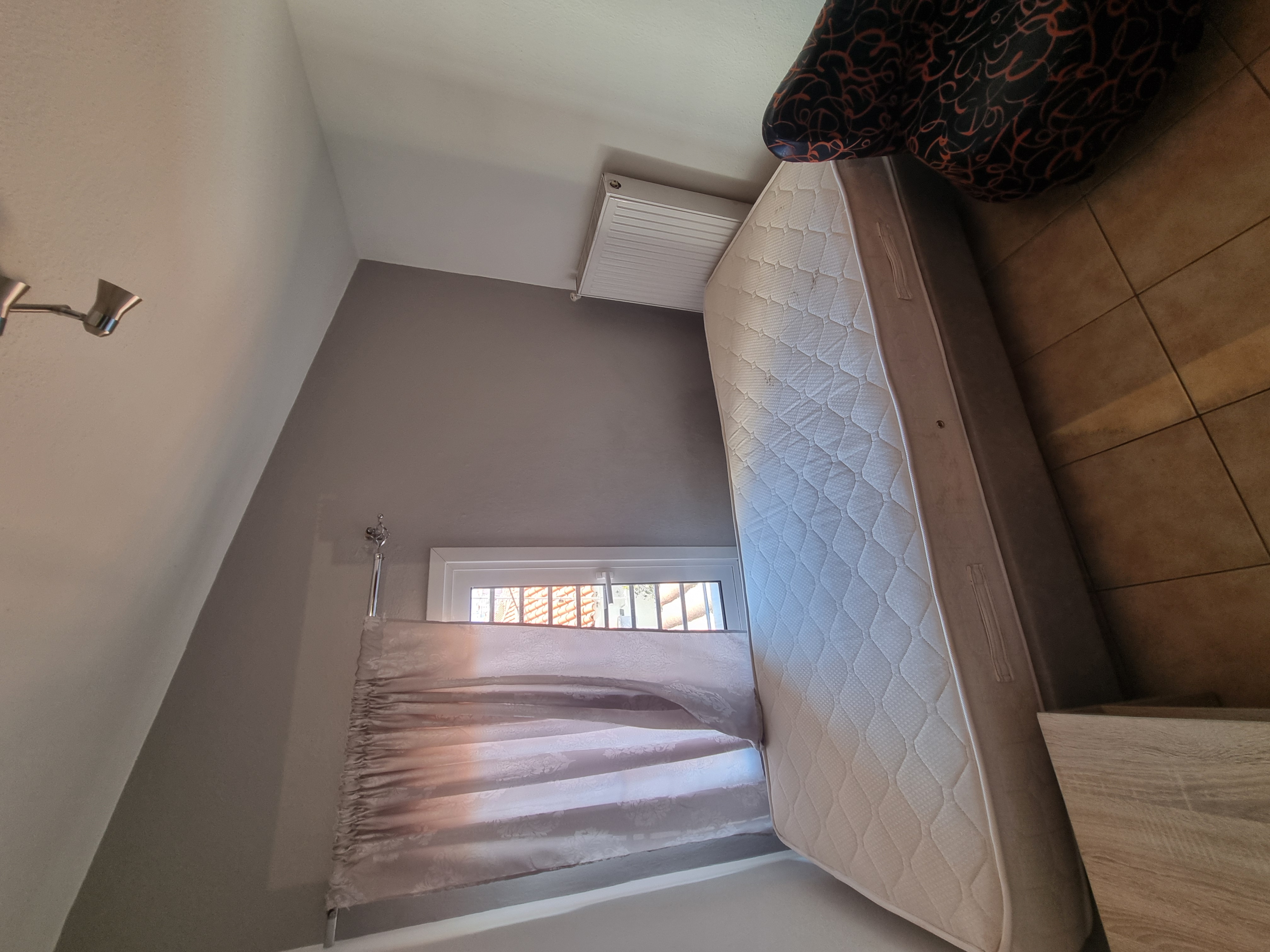 Polychrono Seabreeze Balcony Apartment double bed beside a curtained window