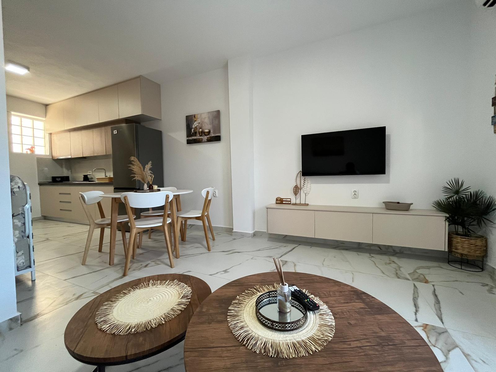 Aegean Dream living room with kitchen, dining table, and TV