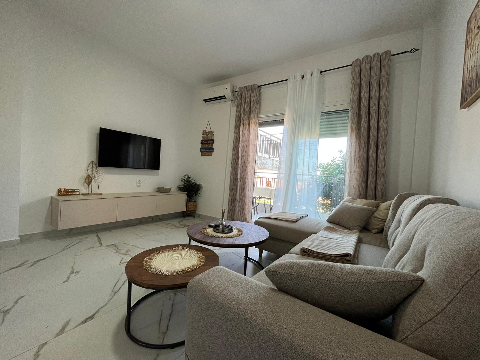 Aegean Dream living room with sofa, TV, and balcony doors